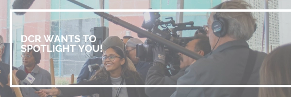 woman holds microphone with other media members to speaker