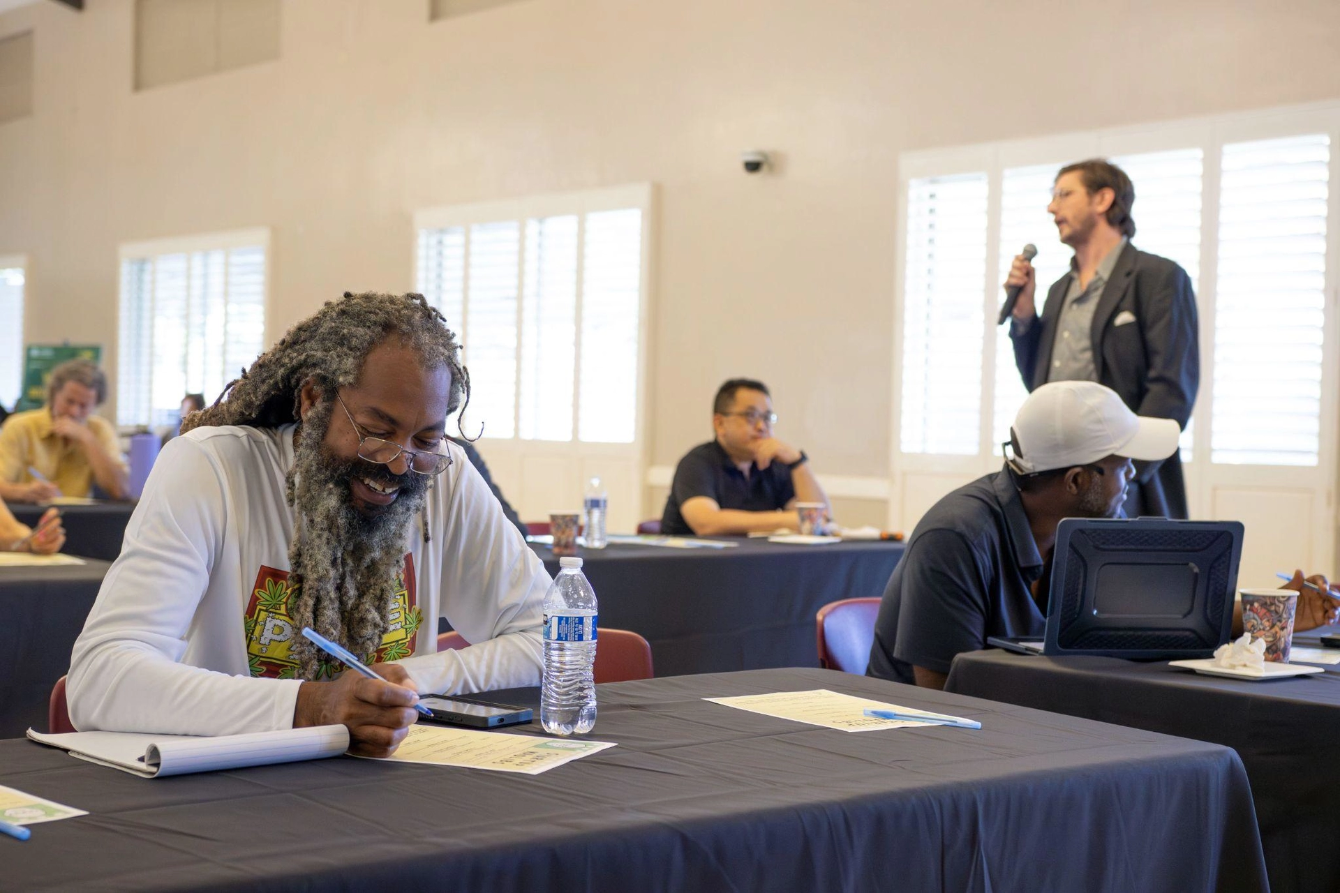 man taking notes while another guest asks a question